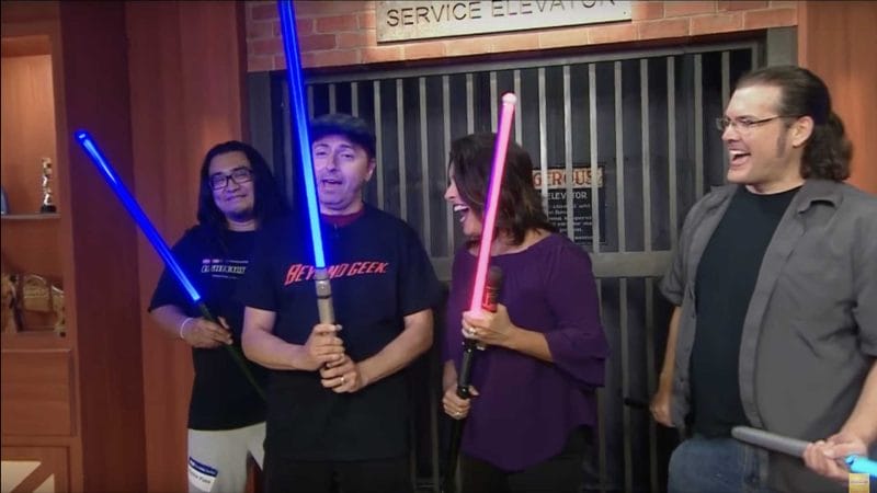 4 people hold lightsabers and laughing