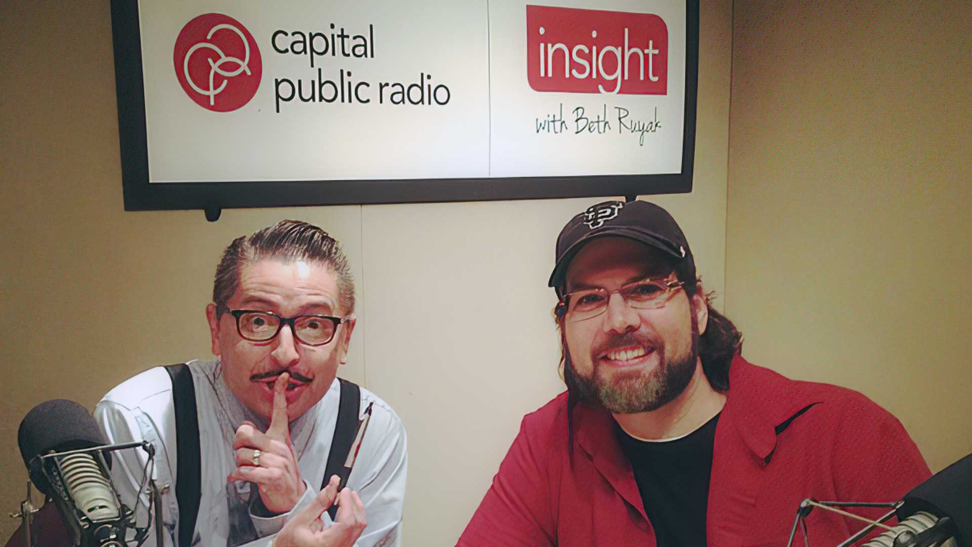 Ein Mann macht „psst“ neben einem anderen Mann, der lächelt