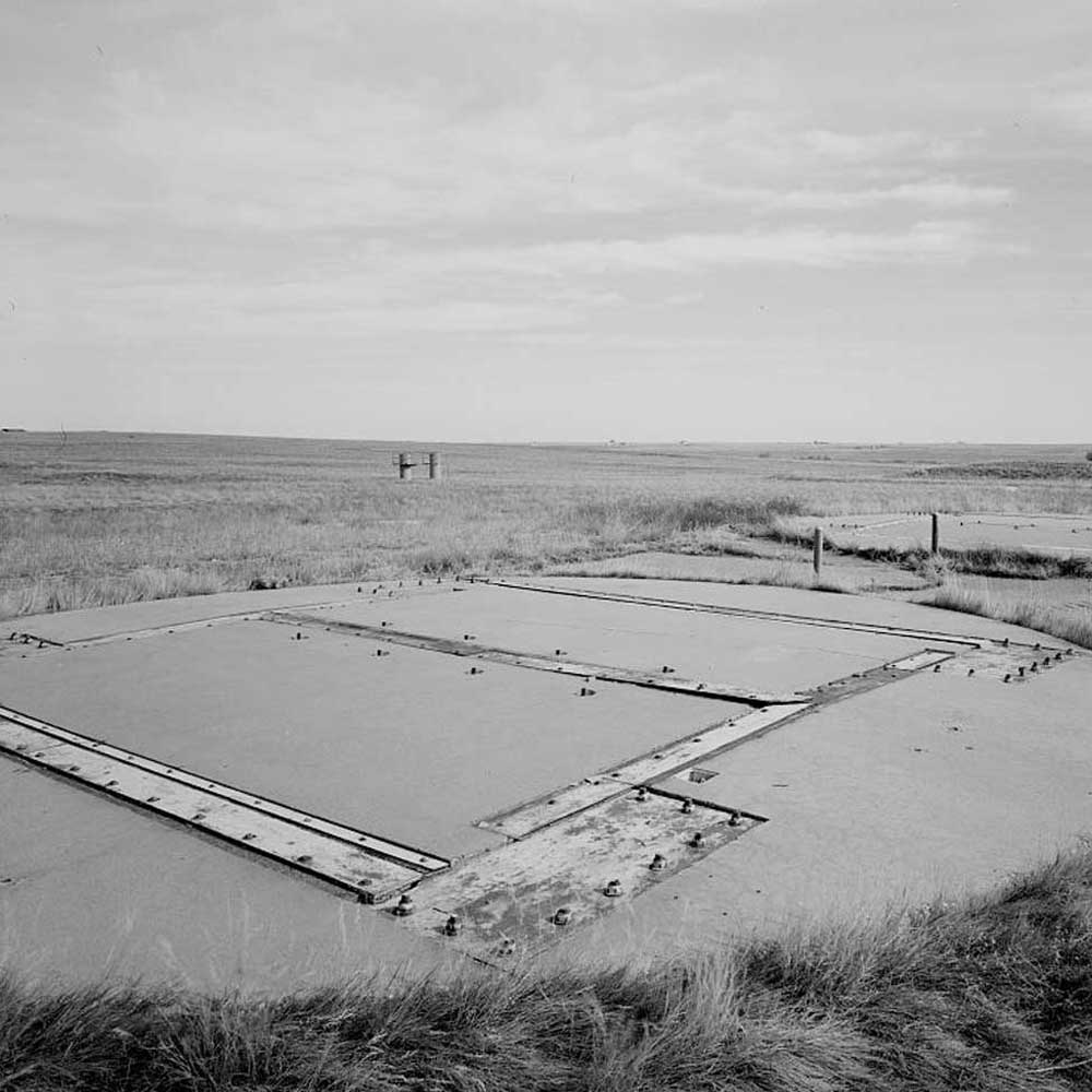 An old black and white photo of a pool in the middle of a field.