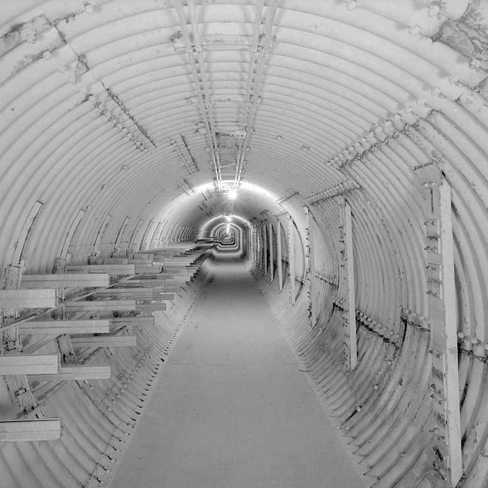 A black and white photo of a tunnel with shelves.