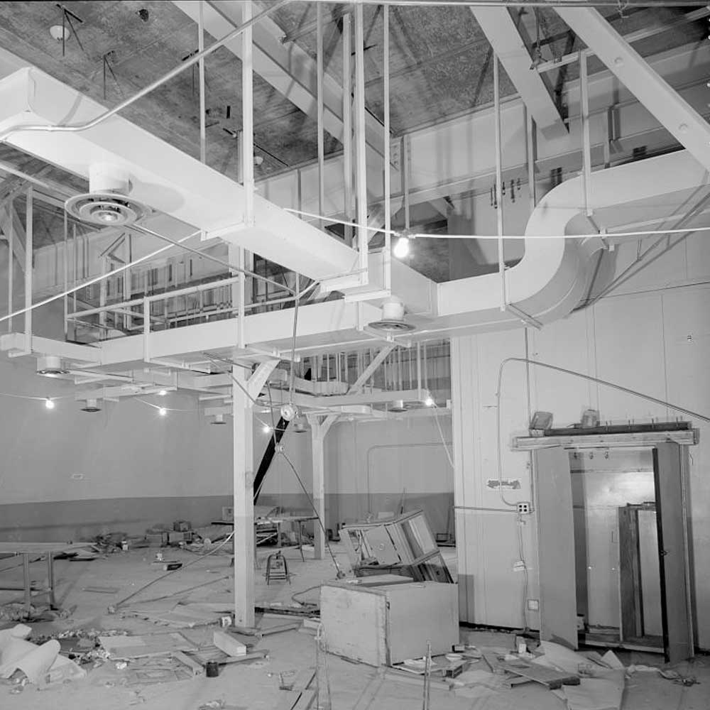 An old black and white photo of a building that is being demolished.